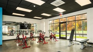 A gym with stationary bikes, a treadmill, and weight machines. - The Hamlet (Saratoga Springs)