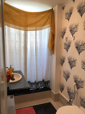 A bathroom with a shower curtain, a sink with a soap dispenser, and a towel rack. - Studio Premium Leblon (Rio de Janeiro)