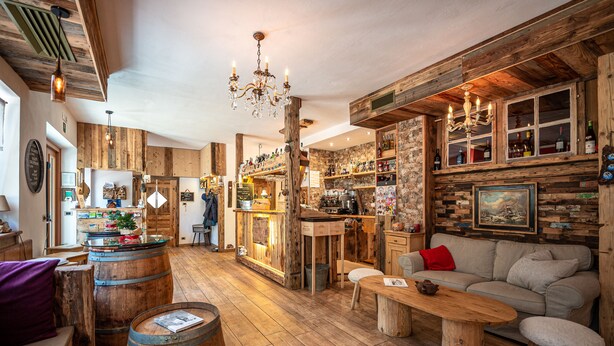 Ein rustikales Interieur mit Holzdielen, einer Bar und einer Sitzecke mit Sofa und Tisch.