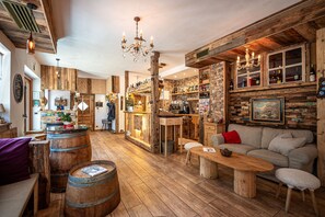 A rustic interior with wooden floors, a bar area, and a seating area with a sofa and table. - Villa Ruggero Wine Hotel (Campitello di Fassa)