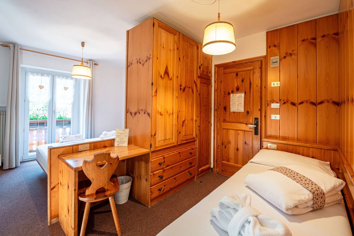 A wooden room with a bed, a desk, and a chair.
