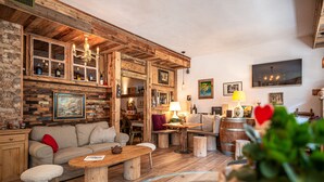 Ein rustikaler Innenraum mit Holzbalken, einer Couch, einem Tisch und einer Bar mit Flaschen.