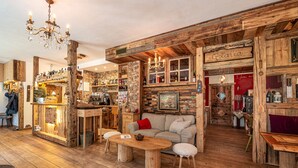 Ein rustikales Interieur mit Holzwänden, einer Bar und einer Sitzecke mit einer Couch und Barhocker.