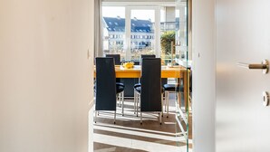 Un área de comedor moderna con un separador de vidrio, una mesa de madera y sillas negras.