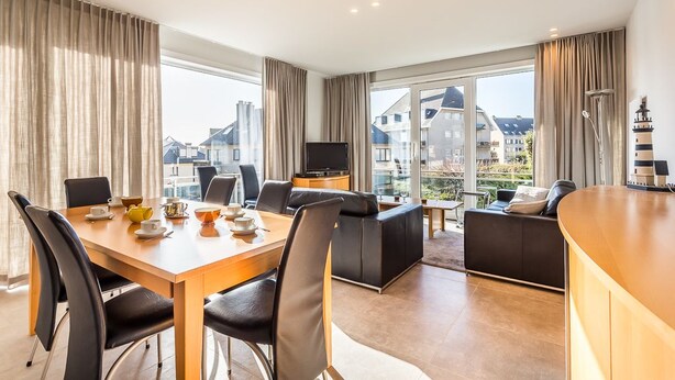 Una habitación de hotel moderna con zona de comedor, sofá y televisión.
