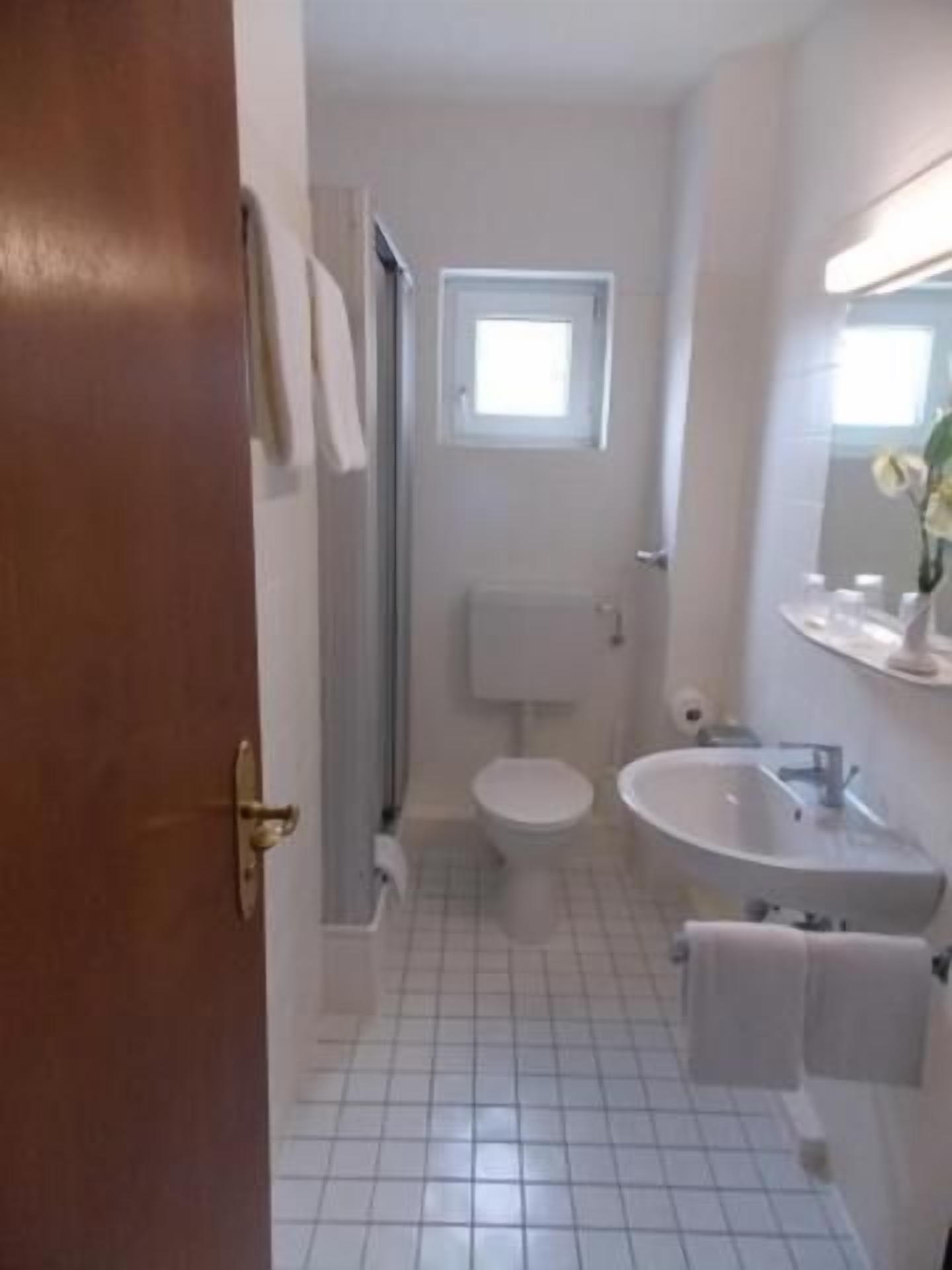 A bathroom with a toilet, sink, and a small window.