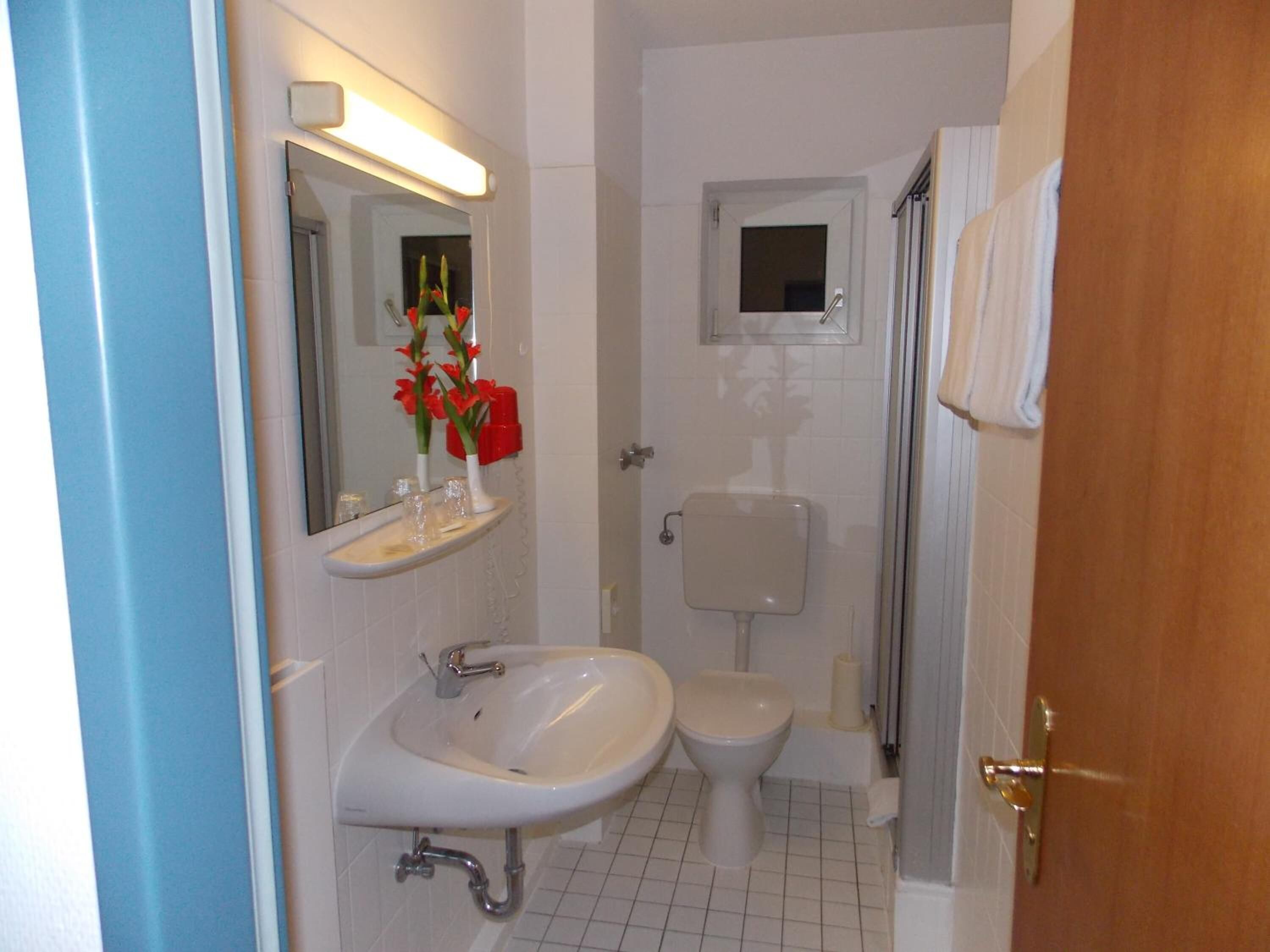 Et badeværelse med vask, toilet og bruser.
