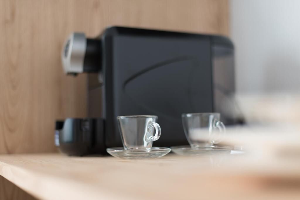 Una cafetera sobre una encimera de madera con dos tazas de vidrio transparente.