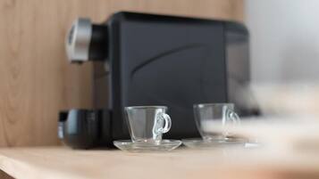 Una cafetera sobre una encimera de madera con dos tazas de vidrio transparente.