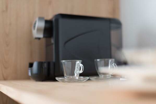 A coffee machine on a wooden counter with two clear glass cups.