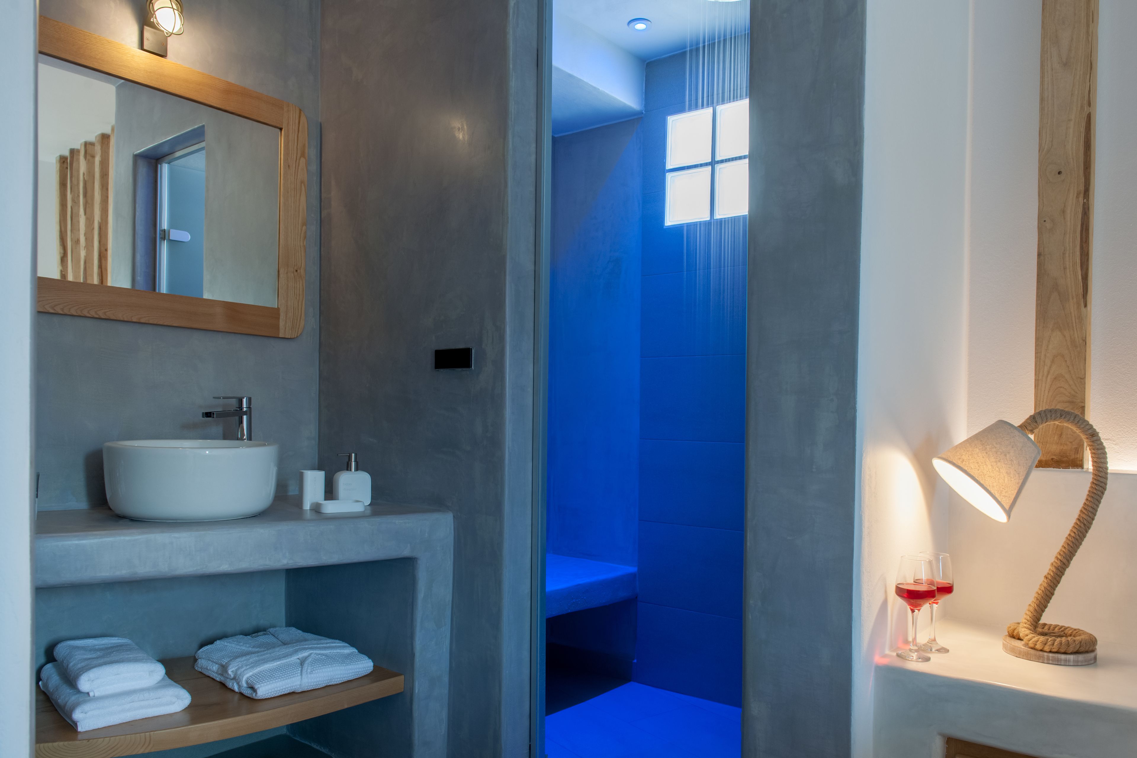 Une salle de bain moderne avec un grand miroir, un lavabo et un espace douche.