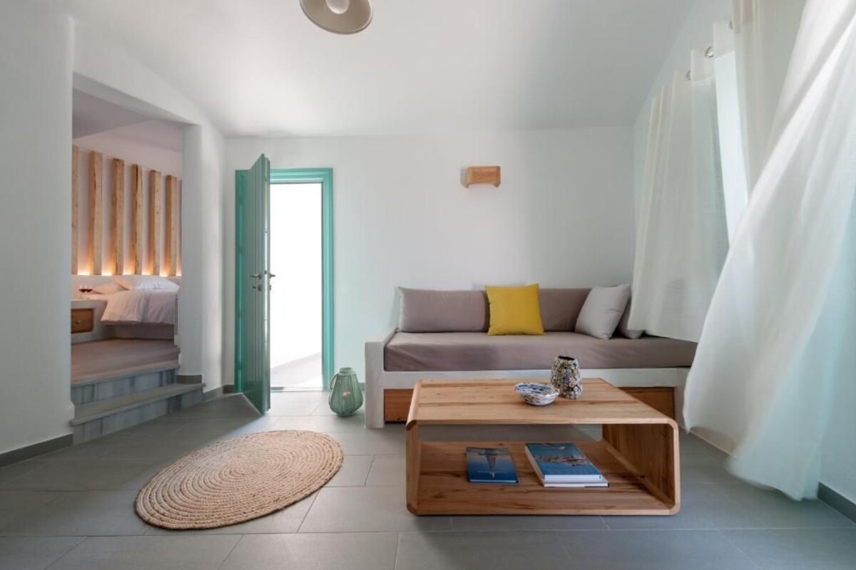 A modern living room with a sofa, coffee table, and a staircase leading to a bedroom.