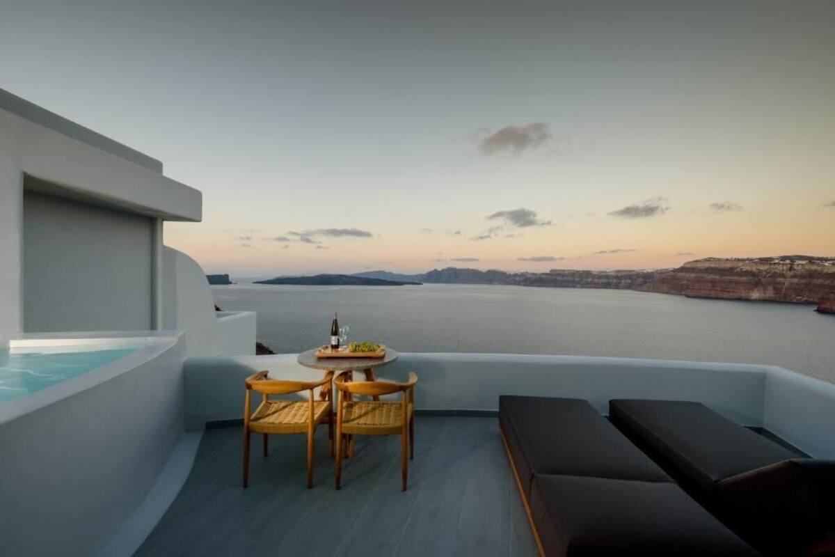 Un balcón con mesa y sillas, un sofá y vistas al mar y los acantilados.