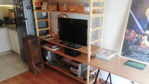 Una oficina en casa con un escritorio de madera, un televisor y diversos objetos en estanterías.