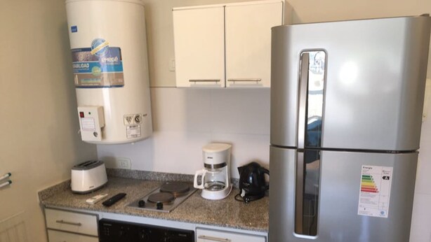A compact kitchenette with a stainless steel refrigerator, a coffee maker, a toaster, and a dishwasher. - Bulnes & Cabrera (Buenos Aires)
