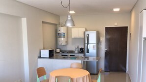 A compact kitchen with a dining area, including a table with chairs, a microwave, a coffee maker, and a refrigerator. - Bulnes & Cabrera (Buenos Aires)