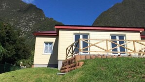 A two-story building with a red roof and a wooden deck. - Ô Coeur De l'île (Salazie)