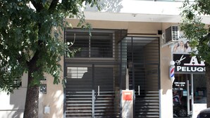 A closed metal shutter door with a sign above it. - Cabrera & Gascon (Buenos Aires)