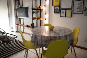 A round dining table with a marble-like tablecloth, surrounded by yellow chairs.