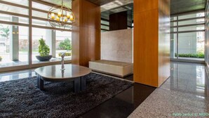 Un hall d’entrée moderne avec une table ronde, un luminaire suspendu et de grandes fenêtres.