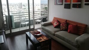 Un salon moderne avec un canapé, une table basse et des fauteuils, le tout près d’une grande porte-fenêtre coulissante.