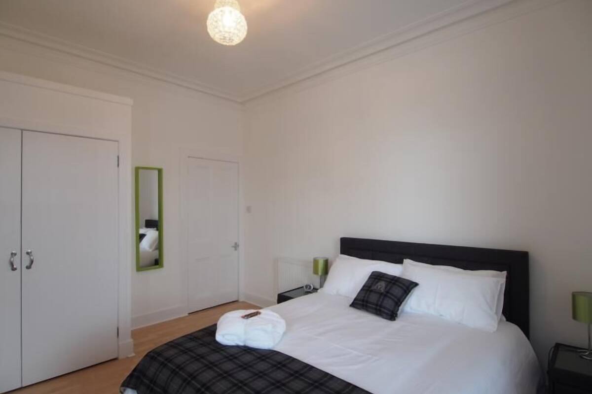 A neatly arranged bedroom with a bed, a wardrobe, a mirror, and a bedside table.