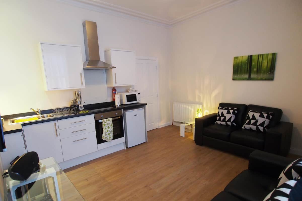 A compact living space with a kitchenette, a dining table, and a sofa.