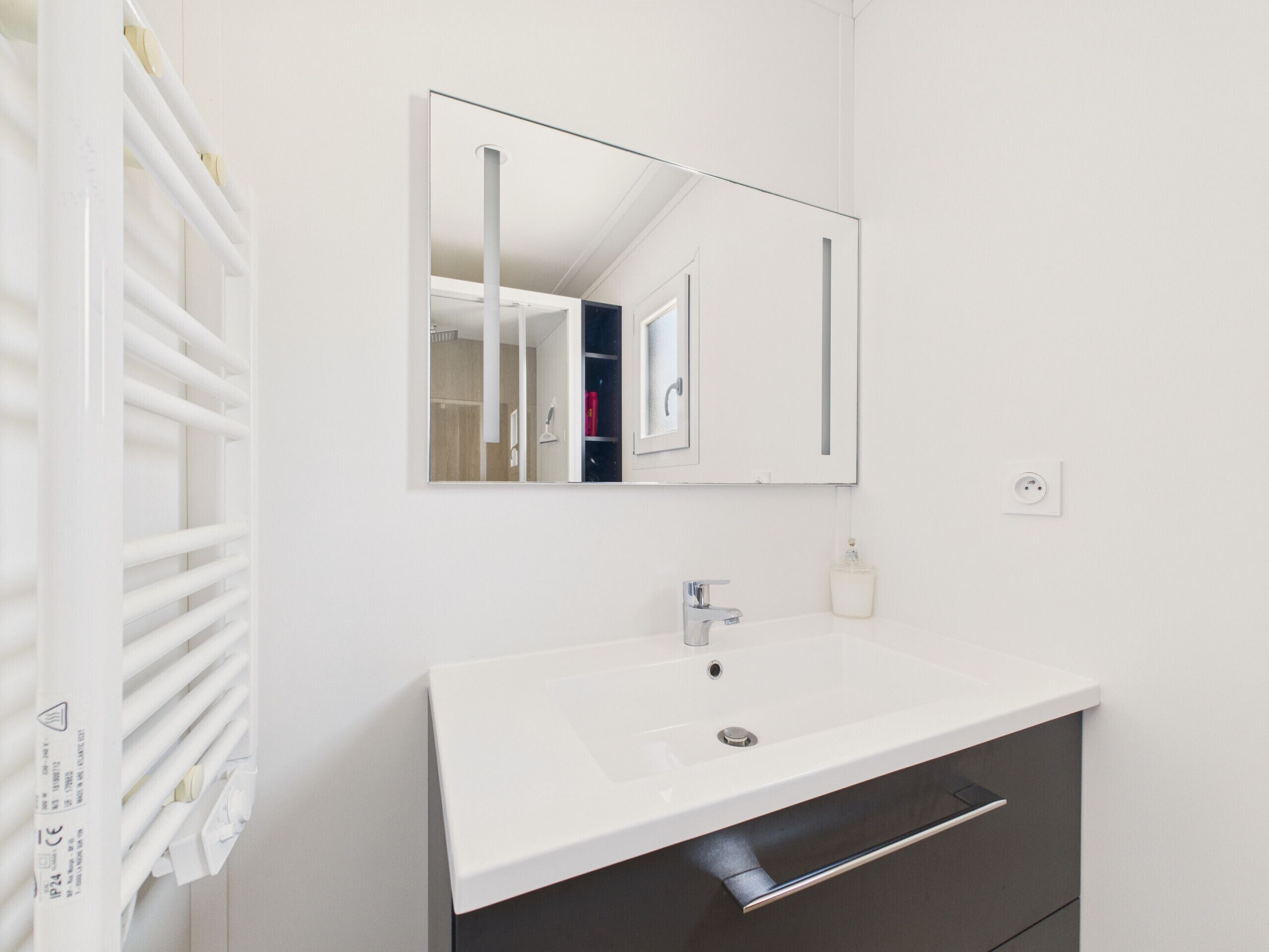 A modern bathroom with a white sink, a mirror, and a towel rack.
