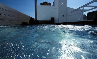 Una piscina al aire libre, sombrillas, sillones reclinables de piscina