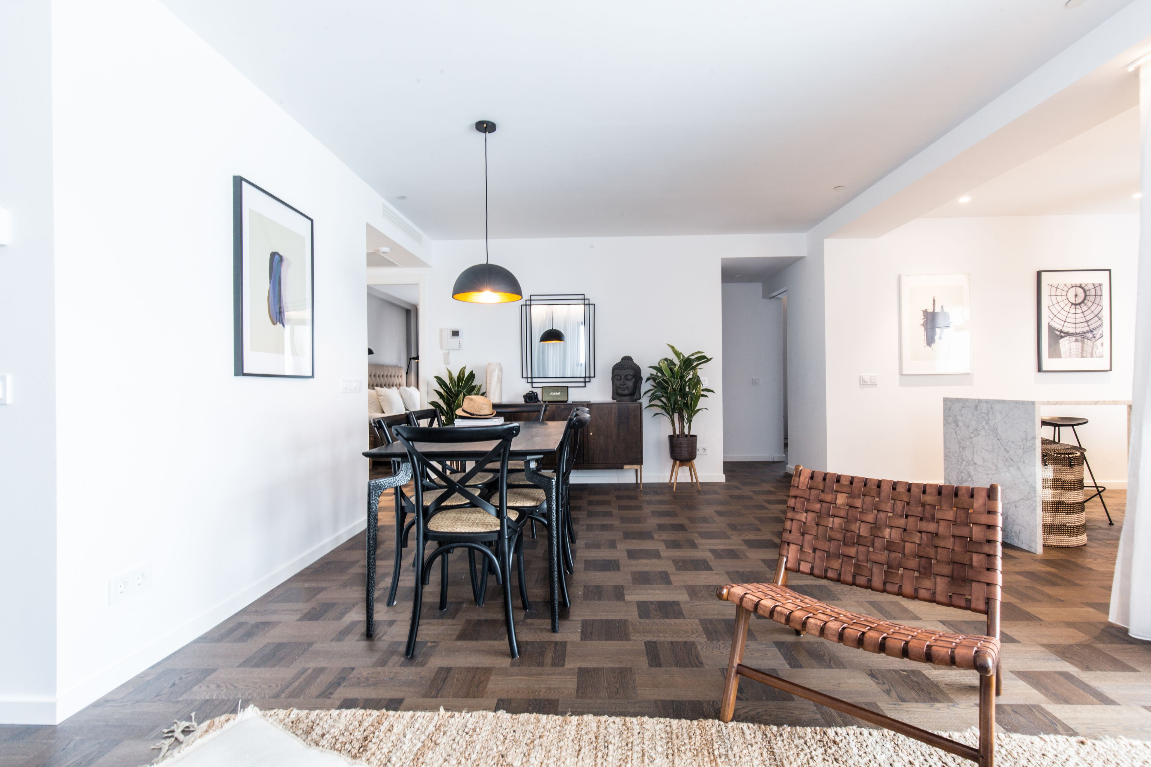 Ein modernes Wohnzimmer mit Essbereich, mit Holzboden, einer gewebten Bank und einem Esstisch mit Stühlen.