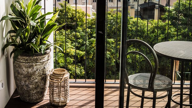 A balcony with a potted plant, wicker basket, and a metal table and chair. - Terreno Suites (Palma de Mallorca)