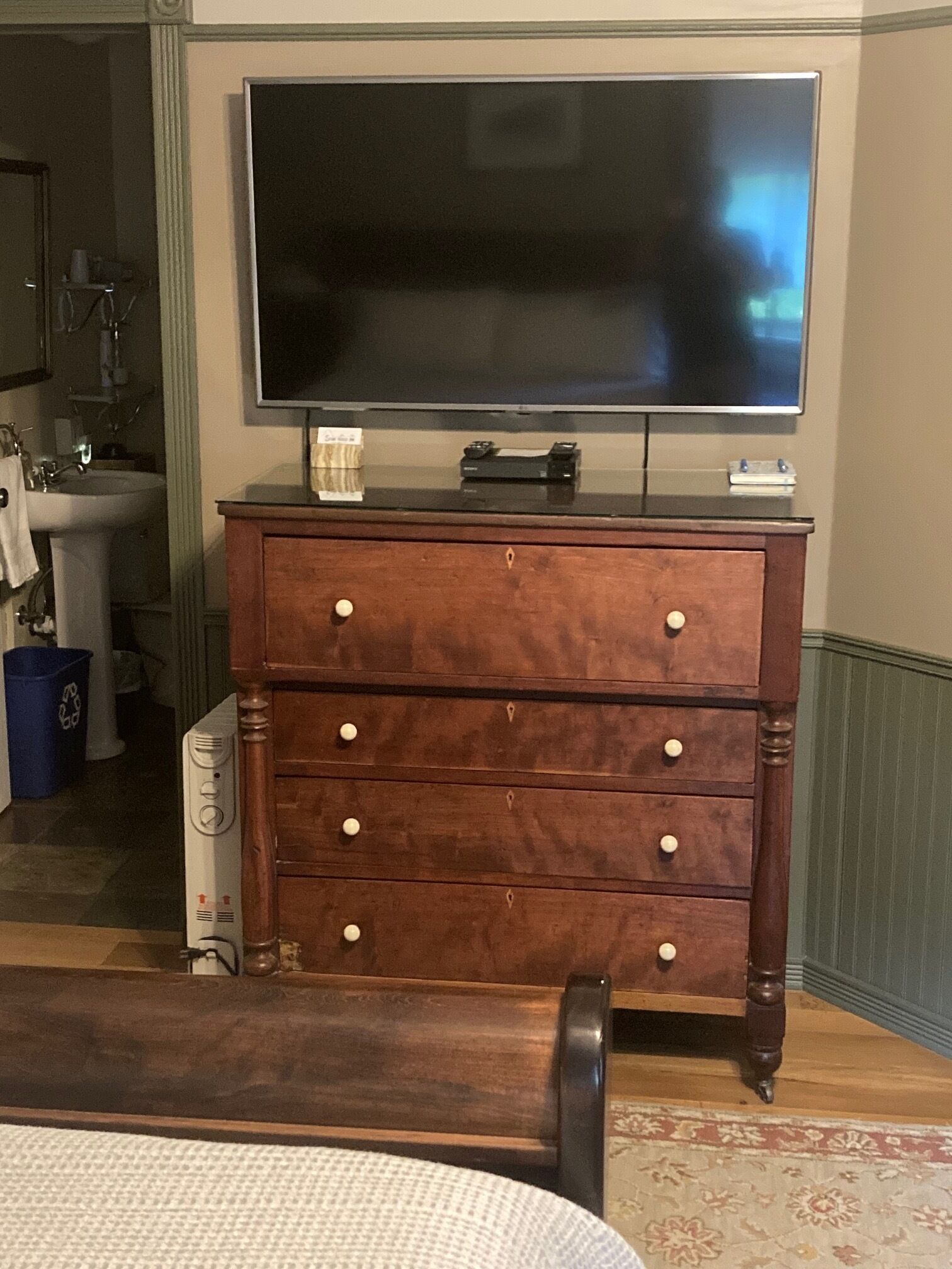 A wooden dresser with drawers and a flat-screen TV on top.