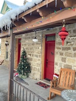 A stone building with a red door and a Christmas tree.
