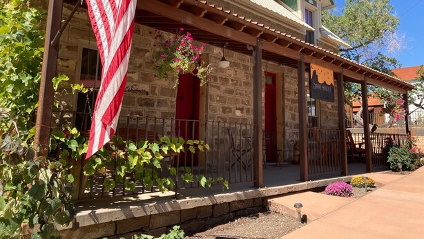 Un bâtiment rustique en pierre, doté d’un porche, d’un drapeau américain et d’une enseigne indiquant « Stone House Inn ».