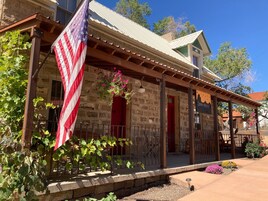 A rustic stone building with a porch, an American flag, and a sign that reads "Stone House Inn."