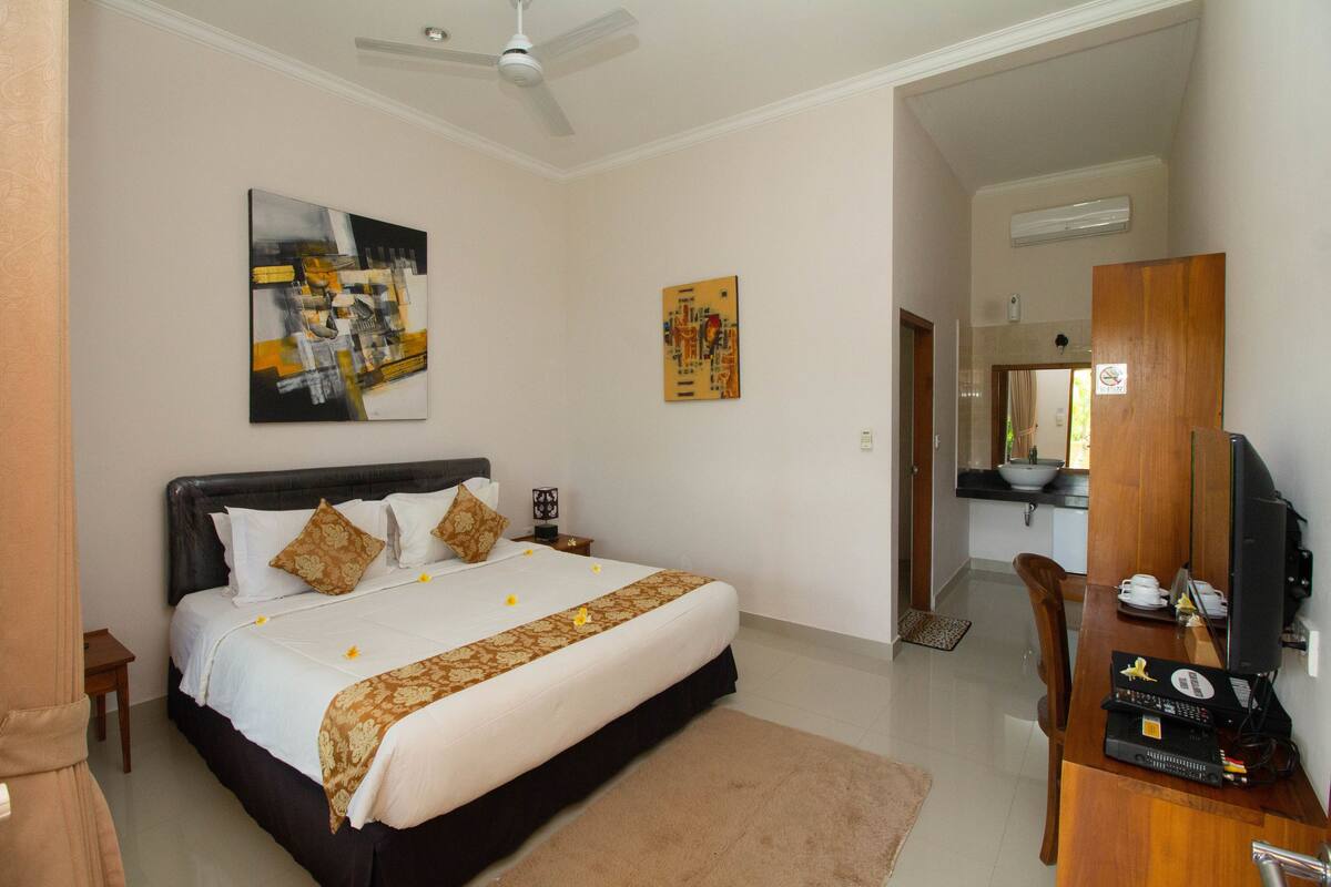 A hotel room with a bed, a desk with a computer, and artwork on the walls.