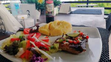 Prato com purê de batata, salada e um prato de carne, acompanhado de uma garrafa de vinagre balsâmico.
