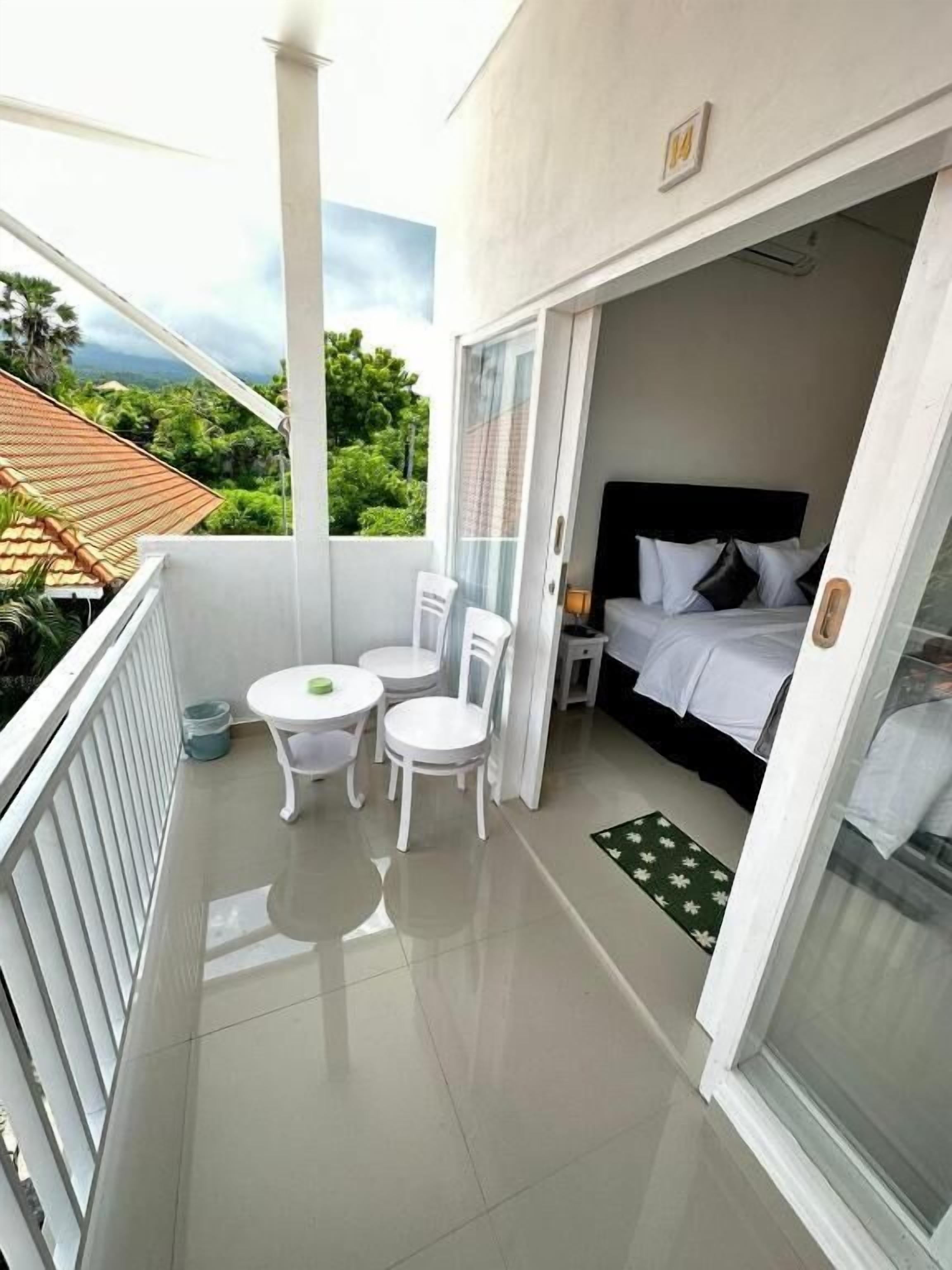 A balcony with a bed, a table, and two chairs.