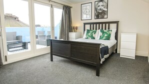 A bedroom with a bed, a nightstand, a dresser, and a view of the outside through a sliding glass door. - Brighton Lanes Townhouse Central by Brighton Holiday Lets (Brighton)