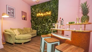 A cozy living room with a green sofa, wooden bar stools, a neon sign, and a wall adorned with foliage. - Brighton Lanes Townhouse Central by Brighton Holiday Lets (Brighton)