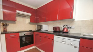 Eine Küche mit roten Schränken, einer Mikrowelle, einem Toaster und einem Geschirrspüler.