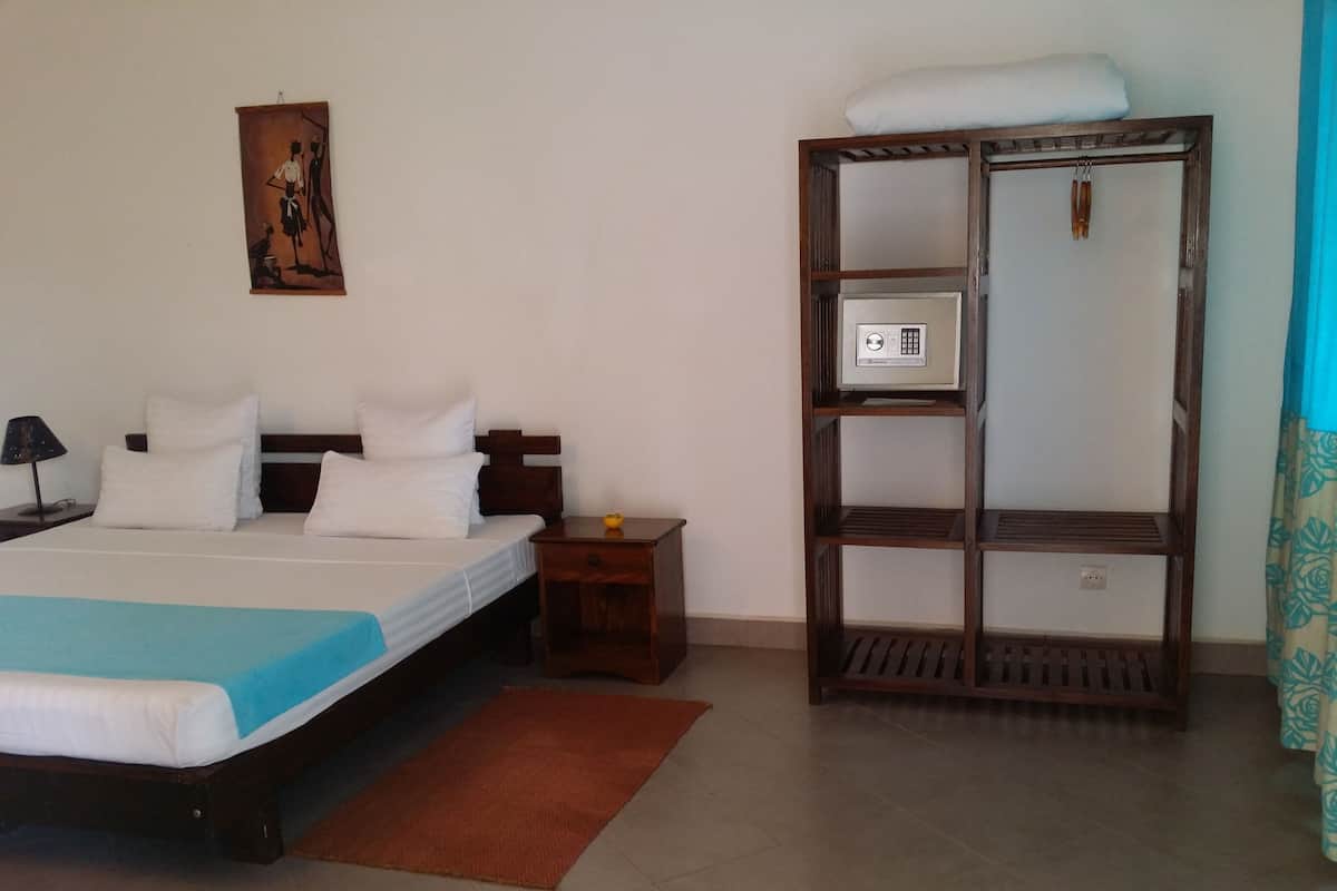 Een hotelkamer met een bed, een nachtkastje, een houten plankunit en een schilderij aan de muur.