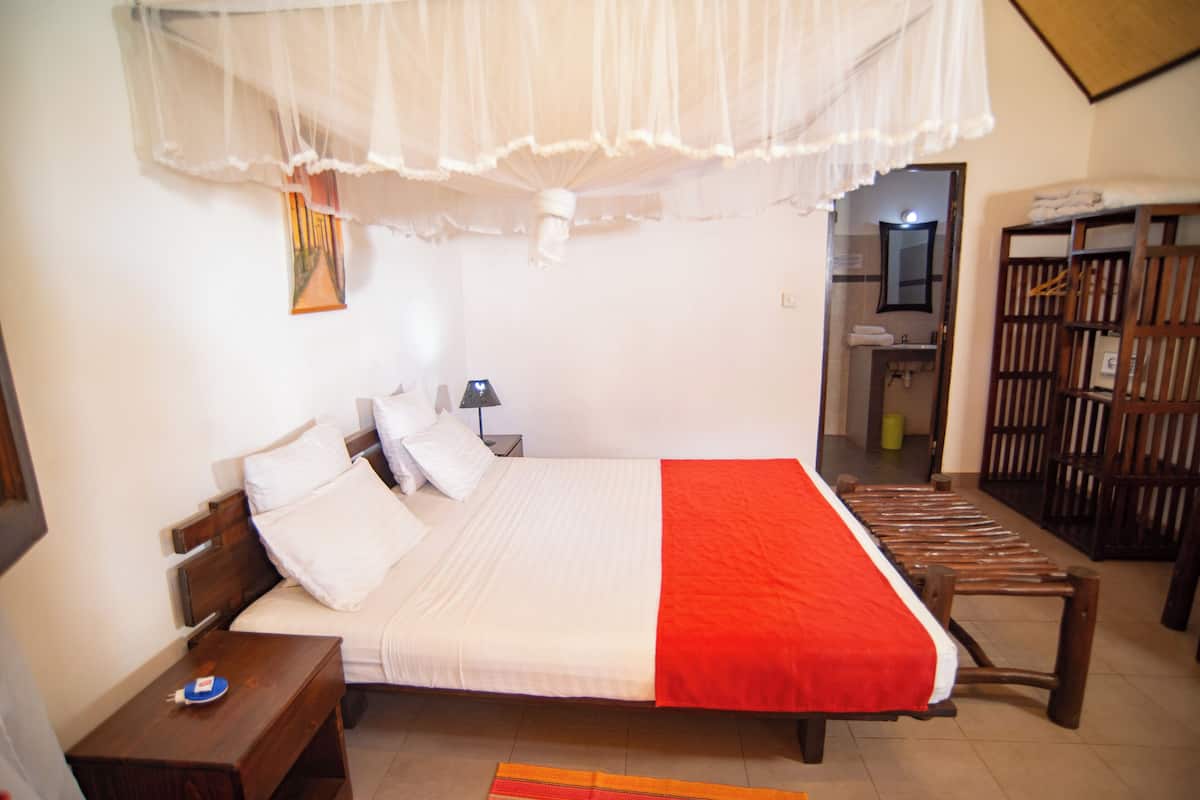 Een slaapkamer met een bed, nachtkastje en een houten bankje.