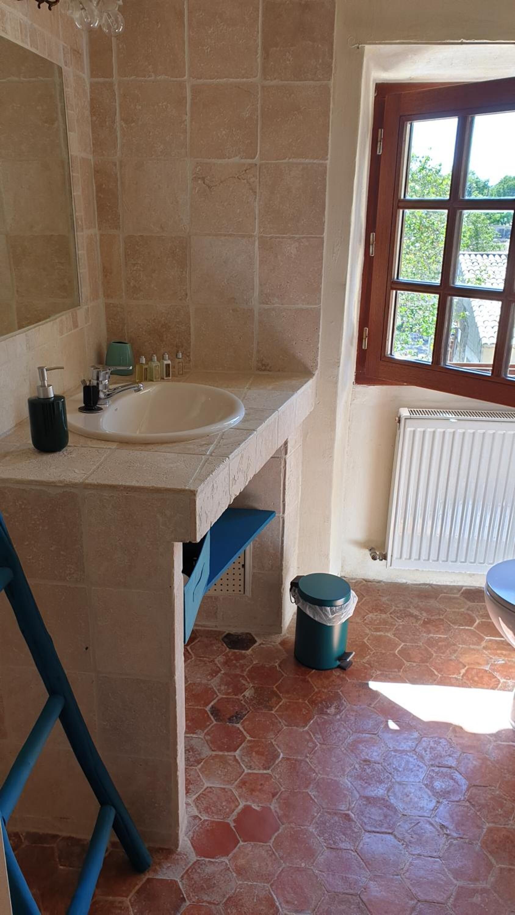 A bathroom with a large sink, a mirror, a window with a view, and a radiator.