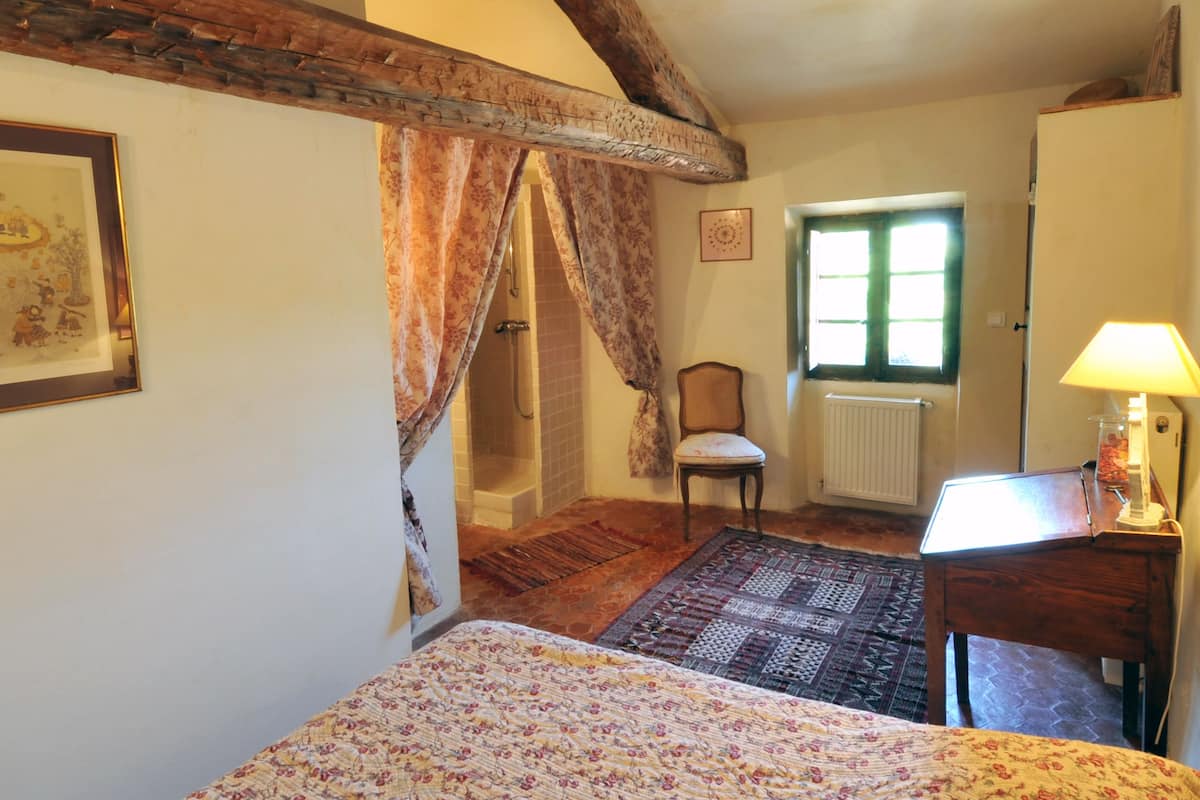 Un dormitorio con una cama, una silla, un escritorio, una ventana y un radiador.