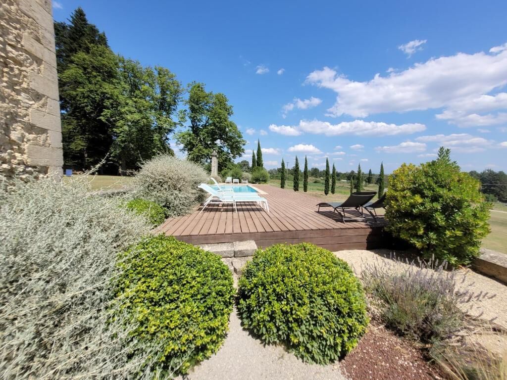 A pool area with a wooden deck, lounge chairs, and a clear sky.