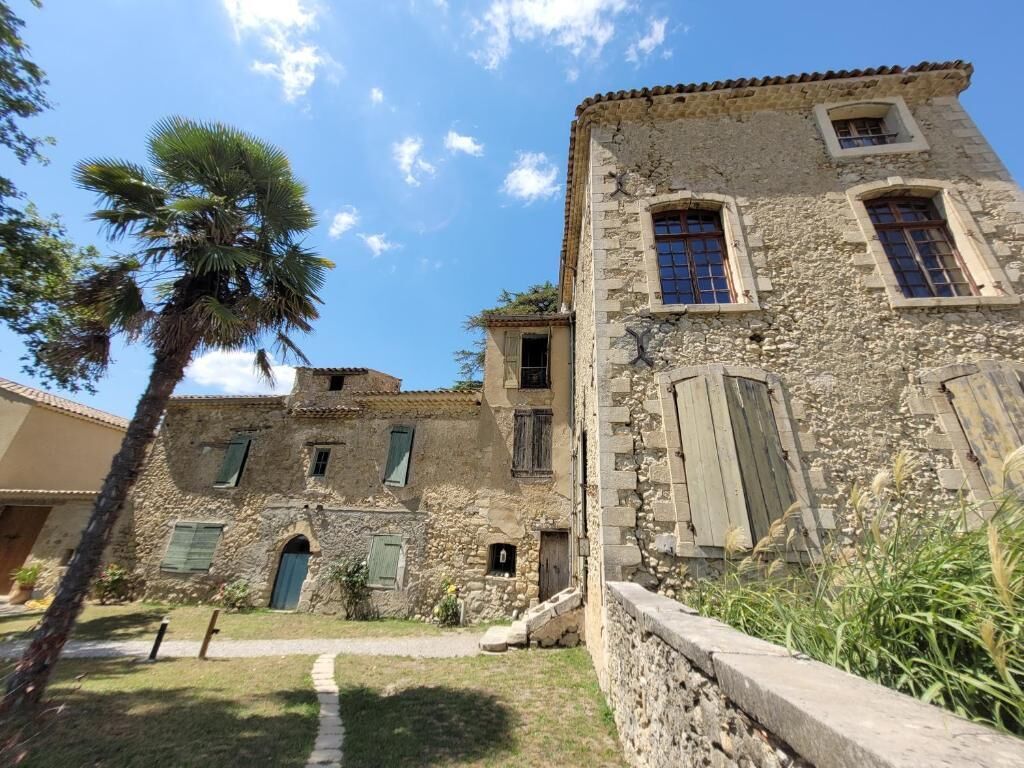 A stone building with multiple windows and a palm tree in the foreground.