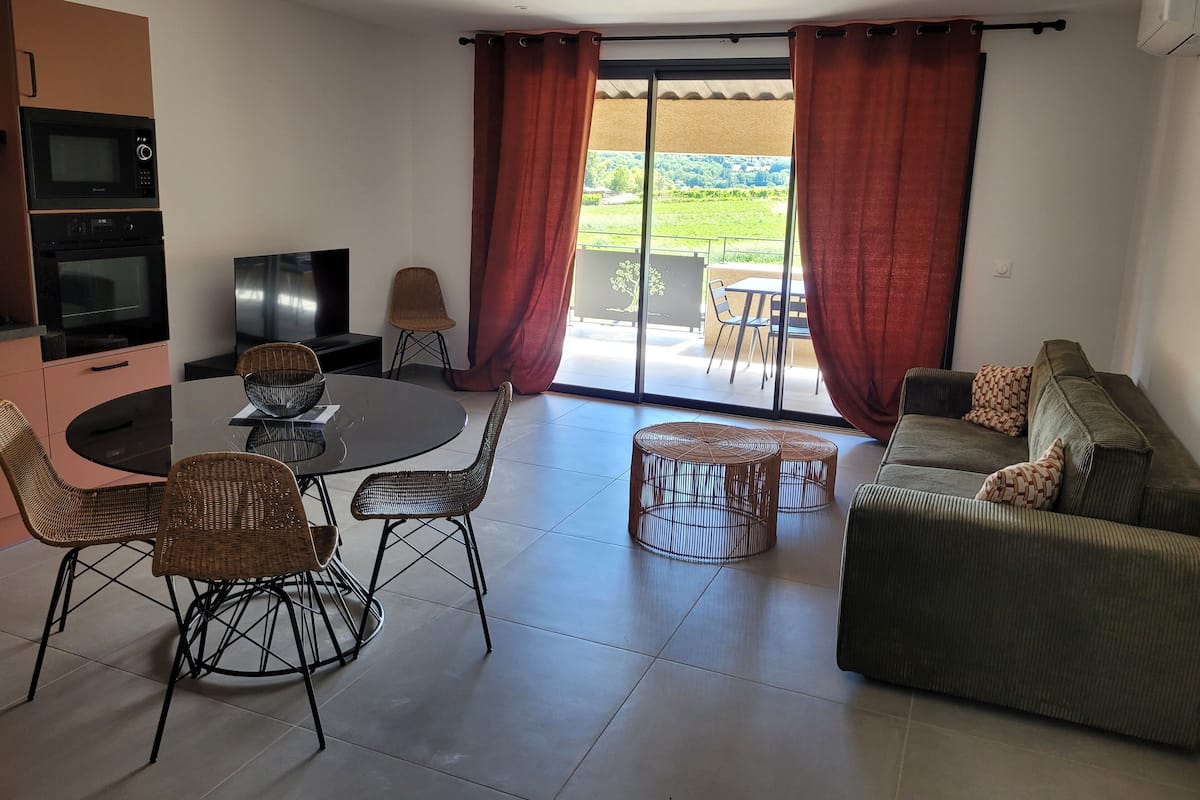 Una sala moderna con comedor, un sofá y un televisor.