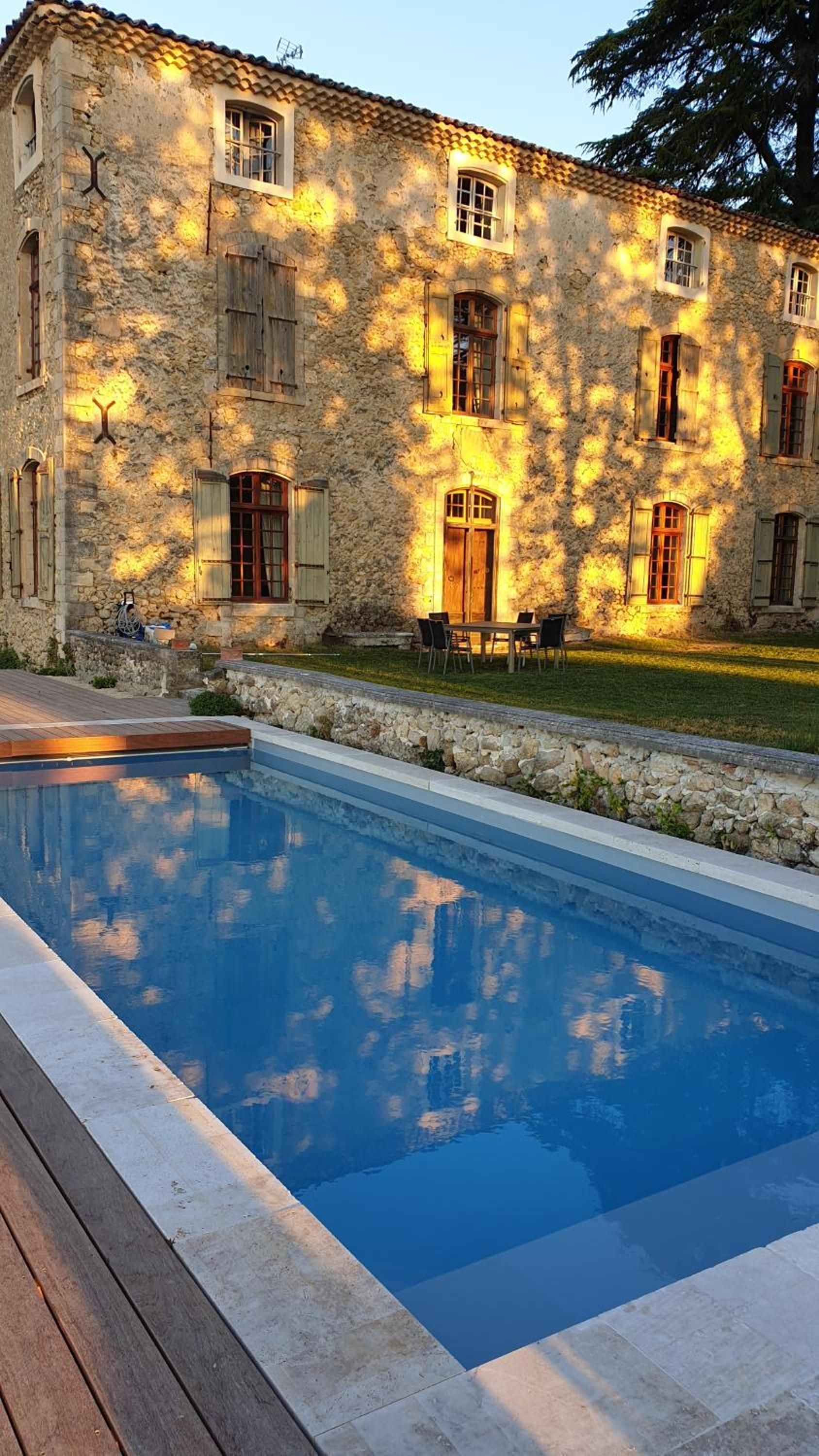 Un bâtiment en pierre doté d’une piscine et d’un espace extérieur aménagé pour se détendre.