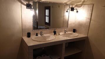 Een badkamer met twee wastafels, een spiegel en een douche.